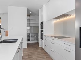 A kitchen with white cabinets and a stove at Langs Life - Waipu Holiday Home, Waipu Cove