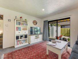 A living room with a television and bookshelf at Magnolia Cottage - Nelson Holiday Homes Levin