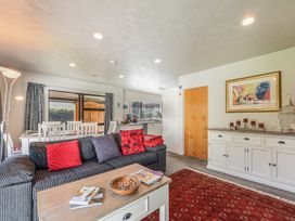 A living room with a sofa and dining table at Magnolia Cottage - Nelson Holiday Homes Levin