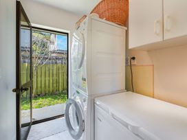 A laundry room with a washing machine and dryer at Magnolia Cottage - Nelson Holiday Homes Levin