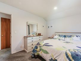 A bedroom featuring a bed, dresser, and mirror at Magnolia Cottage - Nelson Holiday Homes in Levin