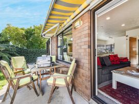 An outdoor seating area with a table and chairs at Magnolia Cottage - Nelson Holiday Homes Levin