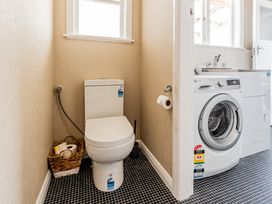 A bathroom with a toilet and washing machine at Home away from Home - Levin Holiday Home, Foxton