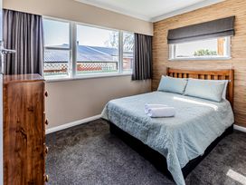 A bedroom with a bed and windows at Home away from Home - Levin Holiday Home in Foxton
