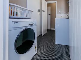 A laundry room with a washing machine and basket at Home away from Home - Levin Holiday Home Foxton