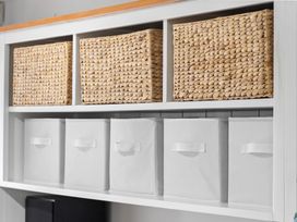 A shelf with woven baskets and storage bins at Westlight Apartment - Henderson Holiday Home, Auckland