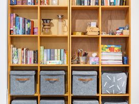 A bookshelf with books and storage bins at Westlight Apartment - Henderson Holiday Home, Auckland