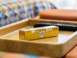A tray with Ferrero Rocher chocolate and a remote control in a living room at Westlight Apartment - Henderson Holiday Home Auckland