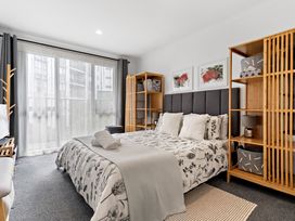 A bedroom with a bed and shelving units at Westlight Apartment - Henderson Holiday Home Auckland
