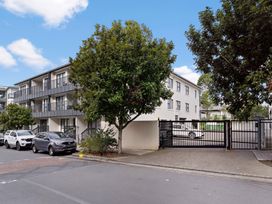 An outdoor area with a building, cars, and a tree at Westlight Apartment - Henderson Holiday Home, Auckland