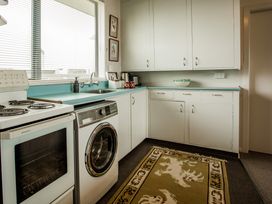 A kitchen with a stove, oven, washing machine, and sink at Southern Base - Te Anau Holiday Home in Te Anau