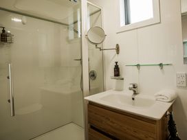 A bathroom with a shower, sink, and mirror at Southern Base - Te Anau Holiday Home in Te Anau