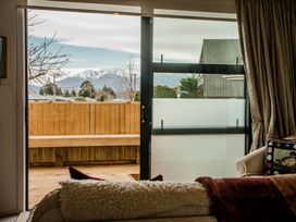 A living room with a view of mountains and a wooden deck at Southern Base - Te Anau Holiday Home Te Anau