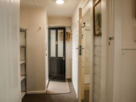 A hallway with a door and shelves at Southern Base - Te Anau Holiday Home, Te Anau
