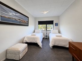 A bedroom with twin beds and a nightstand at Gallery Grove - New Plymouth Holiday Home, New Plymouth