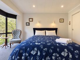 A bedroom with a bed and chair at Gallery Grove - New Plymouth Holiday Home, New Plymouth