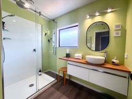 A bathroom with a shower, sink, and mirror at Gallery Grove - New Plymouth Holiday Home, New Plymouth