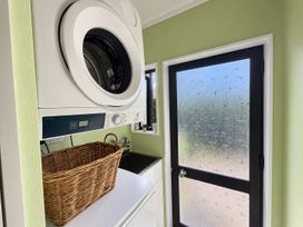 A laundry room with a washing machine and a basket at Gallery Grove - New Plymouth Holiday Home in New Plymouth