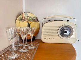 A radio and glassware on a shelf at Gallery Grove - New Plymouth Holiday Home