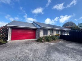 A house with a red garage door and garbage bins at Gallery Grove - New Plymouth Holiday Home, New Plymouth