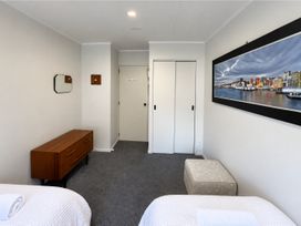 A bedroom with a bed and dresser at Gallery Grove - New Plymouth Holiday Home