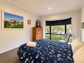 A bedroom with a bed, dresser, and chair at Gallery Grove - New Plymouth Holiday Home in New Plymouth