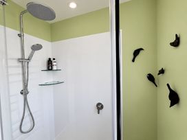 A shower with a showerhead and bottles on a shelf at Gallery Grove - New Plymouth Holiday Home, New Plymouth
