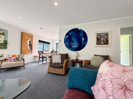 A living room with a sofa, chairs, table and artwork at Gallery Grove - New Plymouth Holiday Home, New Plymouth