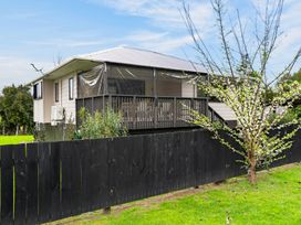 An image of a house with a deck and a tree at Surf House - Mangawhai Heads