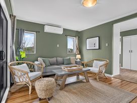 A living room with a sofa and windows at Surf House - Mangawhai Heads Holiday Home Mangawhai Heads