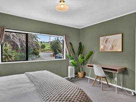A bedroom with a bed and a desk at Surf House - Mangawhai Heads Holiday Home, Mangawhai Heads