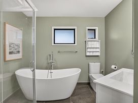 A bathroom with a bathtub, shower, toilet, and sink at Surf House - Mangawhai Heads Holiday Home