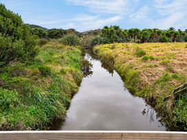 A waterway surrounded by grass and bushes at Surf House - Mangawhai Heads Holiday Home, Mangawhai Heads