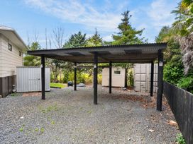 An outdoor carport with storage shed and gravel at Surf House - Mangawhai Heads Holiday Home, Mangawhai Heads