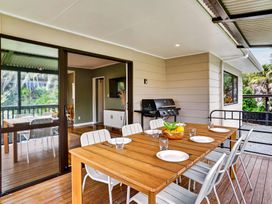 An outdoor dining area with a table and chairs at Surf House - Mangawhai Heads