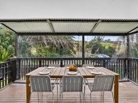 A dining area with a table and chairs overlooking a garden at Surf House - Mangawhai Heads Holiday Home Mangawhai Heads