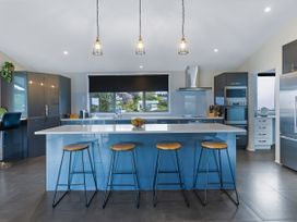 A kitchen with bar stools and an island counter at Natives Nest - Karikari Peninsula