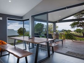 A dining room with a table and bench at Natives Nest - Karikari Peninsula