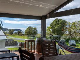 An outdoor area with a table and chairs overlooking a landscape at Natives Nest - Karikari Peninsula