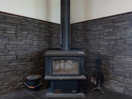 A fireplace with a chimney and tools in the living room at Natives Nest - Karikari Peninsula