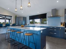 A kitchen with an island and bar stools at Natives Nest - Karikari Peninsula