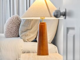 A lamp next to a bed with pillows at Helmstead Cottage - Arrowtown Holiday Home