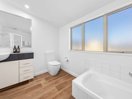 A bathroom with a bathtub, toilet, and sink at Helmstead Cottage - Arrowtown