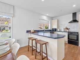 A kitchen with bar stools and a microwave at Helmstead Cottage - Arrowtown