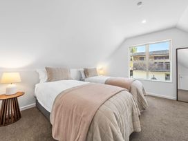 A bedroom with two single beds and a window at Helmstead Cottage - Arrowtown