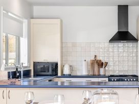 A kitchen with a sink, microwave, kettle, and stove at Helmstead Cottage - Arrowtown