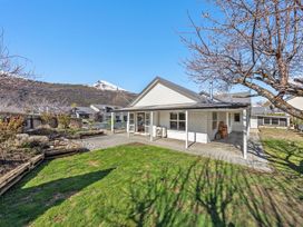 An outdoor view of a house with a yard and mountains in the background at Helmstead Cottage - Arrowtown Holiday Home, Arrowtown