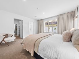A bedroom with a bed and windows at Helmstead Cottage - Arrowtown Holiday Home