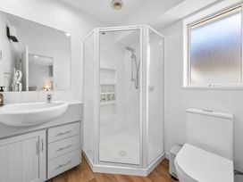 A bathroom with a shower, sink, and toilet at Helmstead Cottage - Arrowtown Holiday Home