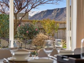 A dining room with a view of the garden and mountains at Helmstead Cottage - Arrowtown